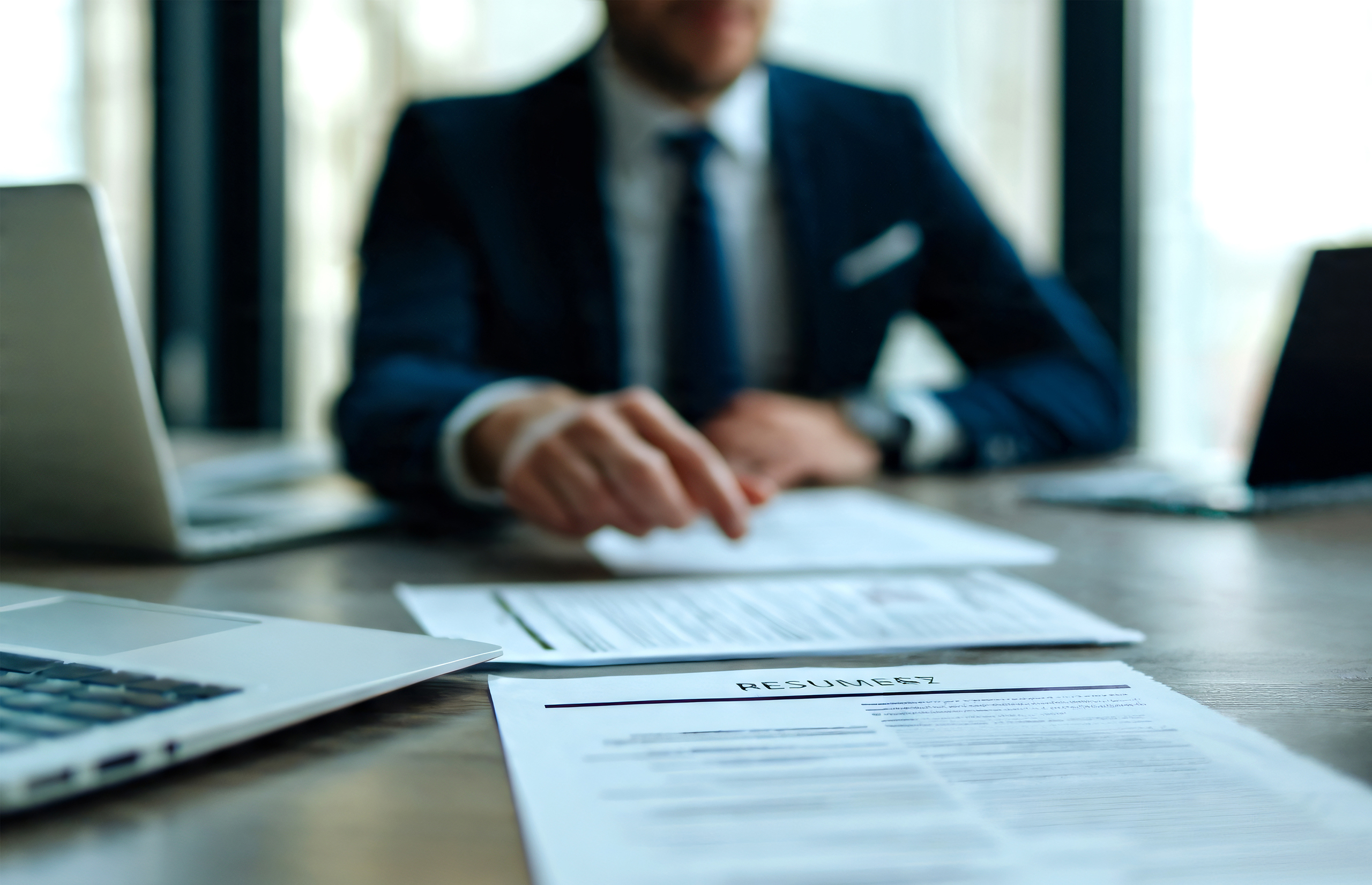 Business leader reviewing paperwork beside a laptop, planning HR services for startups