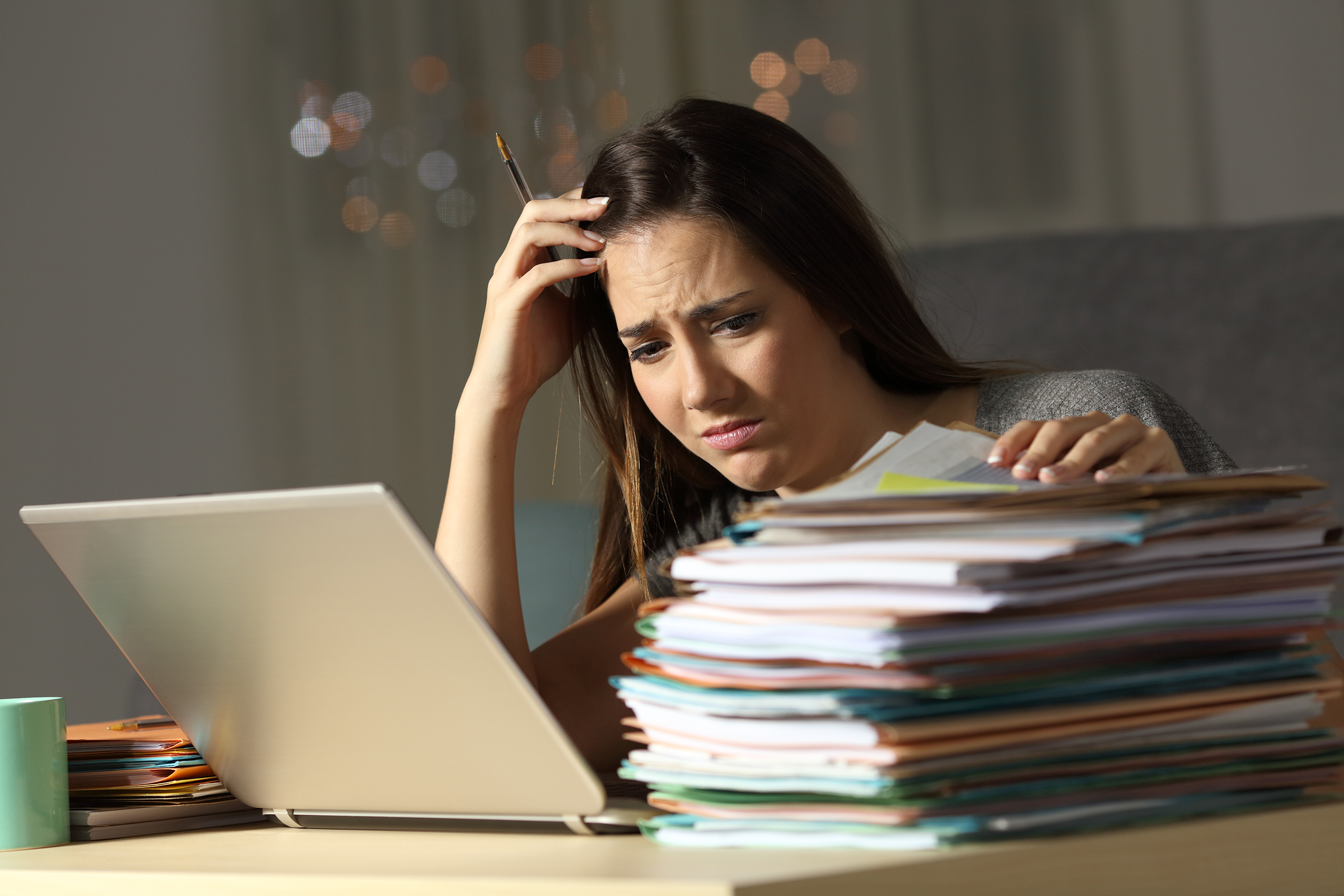 Overwhelmed HR professional beside a stack of files, a sign it's time for managed HR services